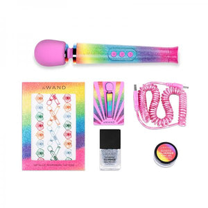 Le Wand All That Glimmers Petite Vibrating Wand with Rainbow Ombre Design and Pink Silicone Head sits next to Le Wand temporary tattoos, a Rainbow Ombre wand enamel pin, pink spiral charging cord, silver glitter nail polish and a small pot of body glitter 